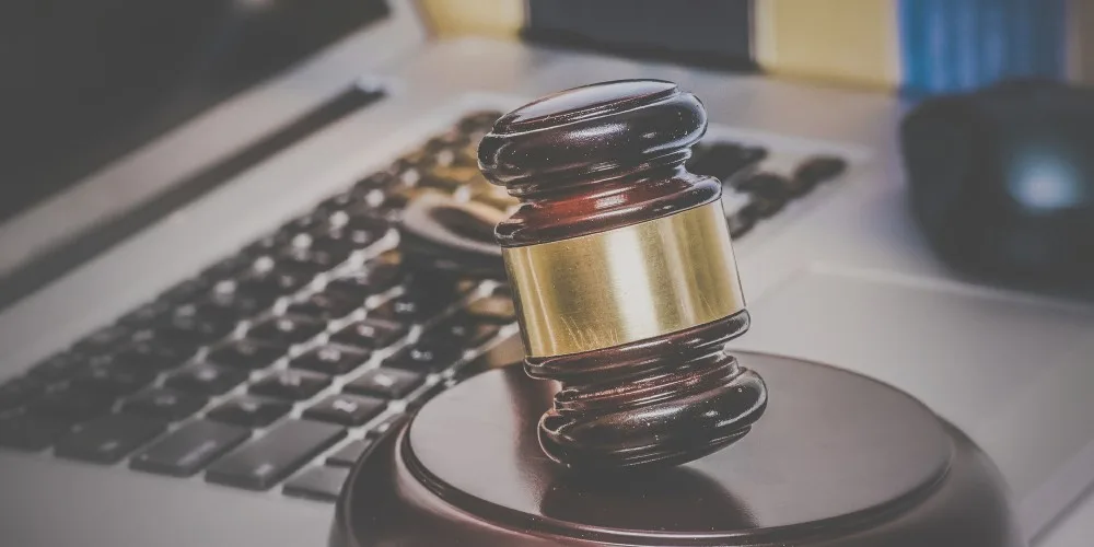 A judge’s gavel resting on a sound block in front of a laptop keyboard, symbolizing digital or online legal proceedings.